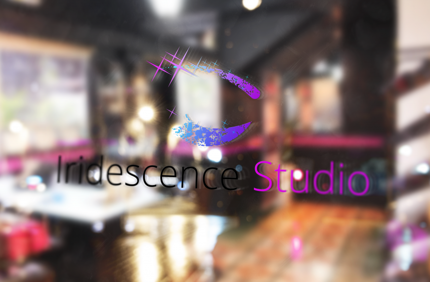 Iridescence studio logo on a plate glass window on the side of an urban street at night